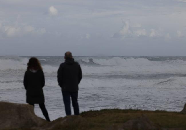 Una pareja contempla el oleaje este domingo en Liencres.