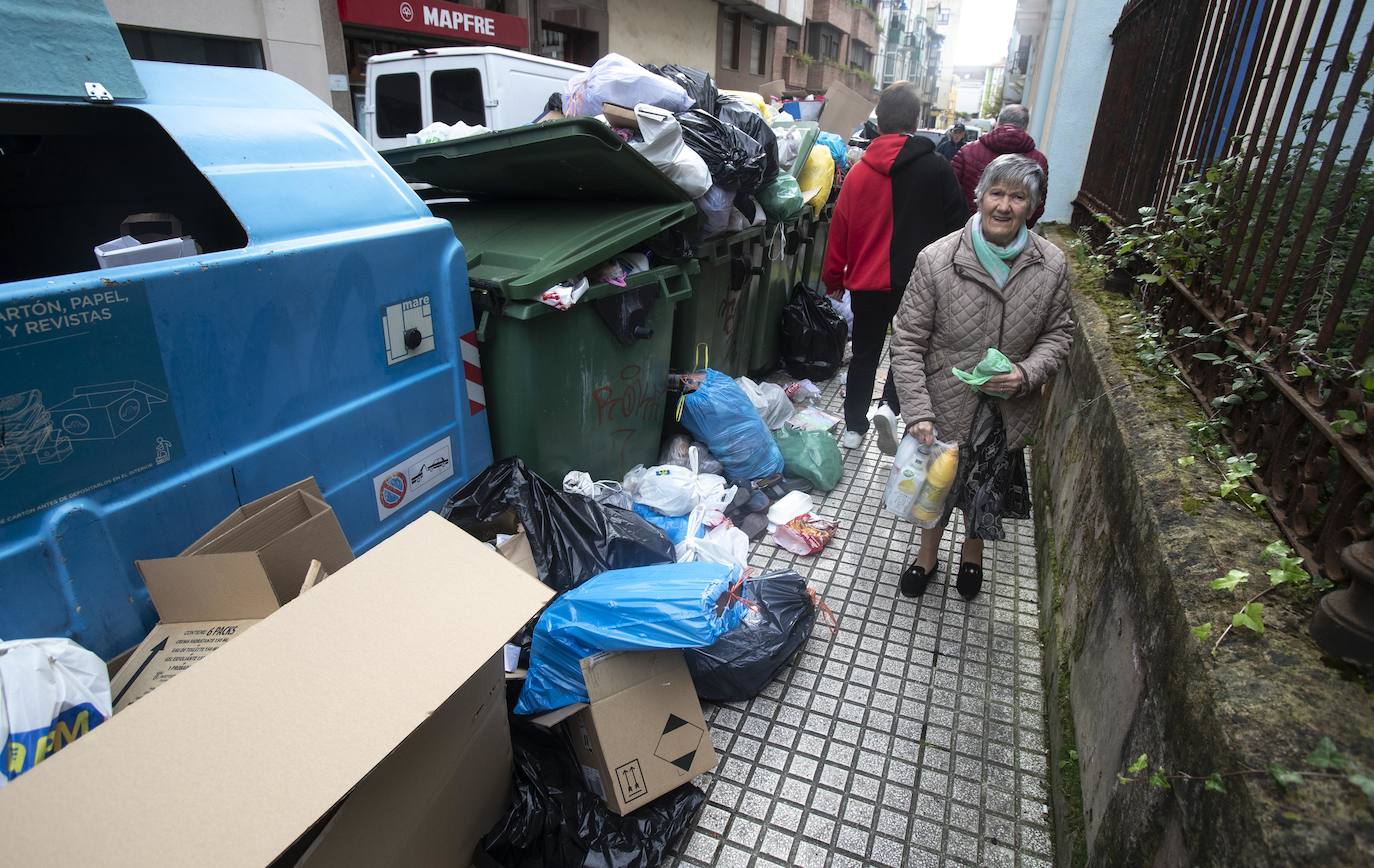 Los vecinos intentan esquivar los residuos que toman la acera para poder transitar.