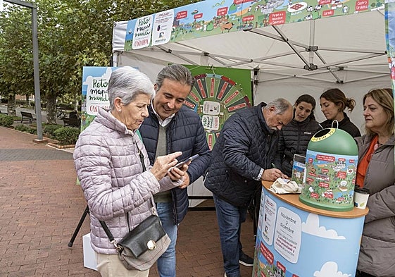 El alcalde de Camargo, Diego Movellán, conversa con una vecina sobre la campaña de recogida de vidrio iniciada en el municipio.