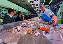 Varios clientes observan el pescado del puesto de Unai, en el Mercado de la Esperanza de Santander.