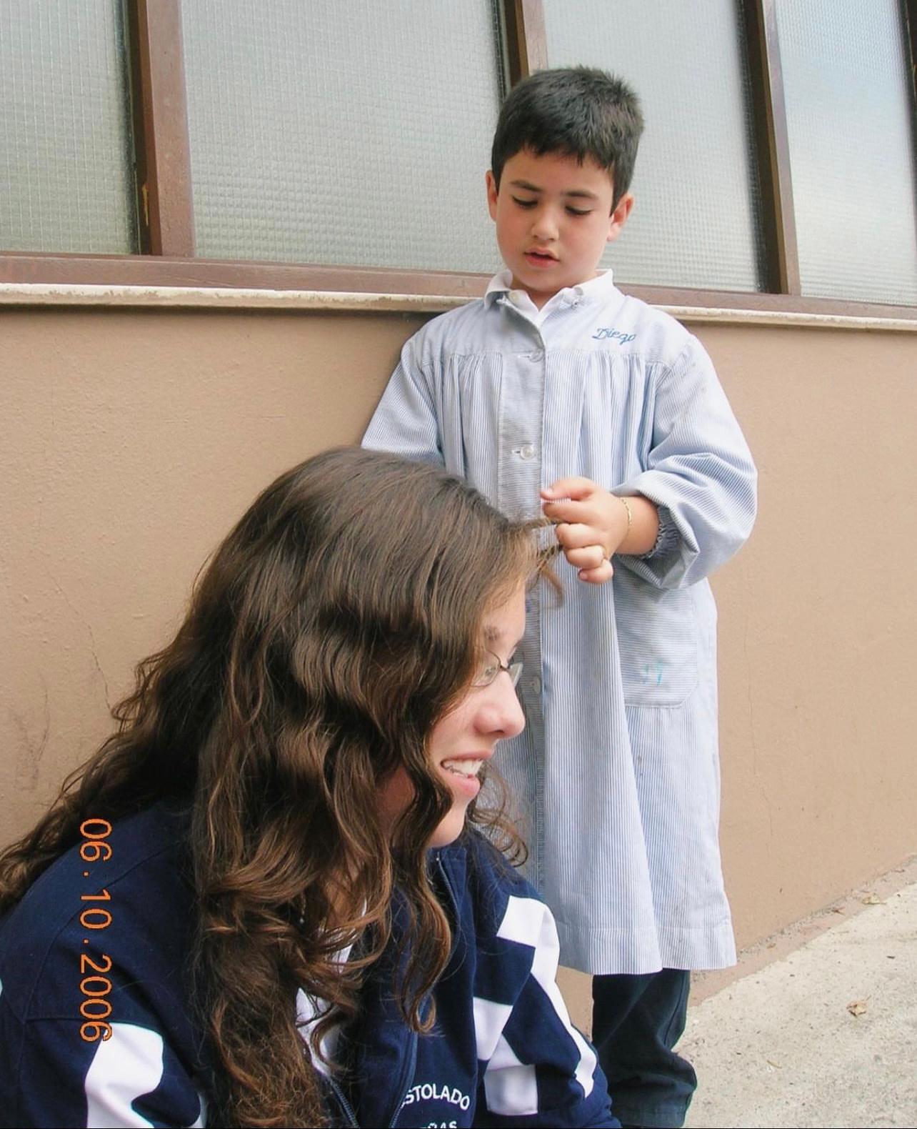 Diego Lainz con con seis años en el patio del colegio peinando a una profesora.