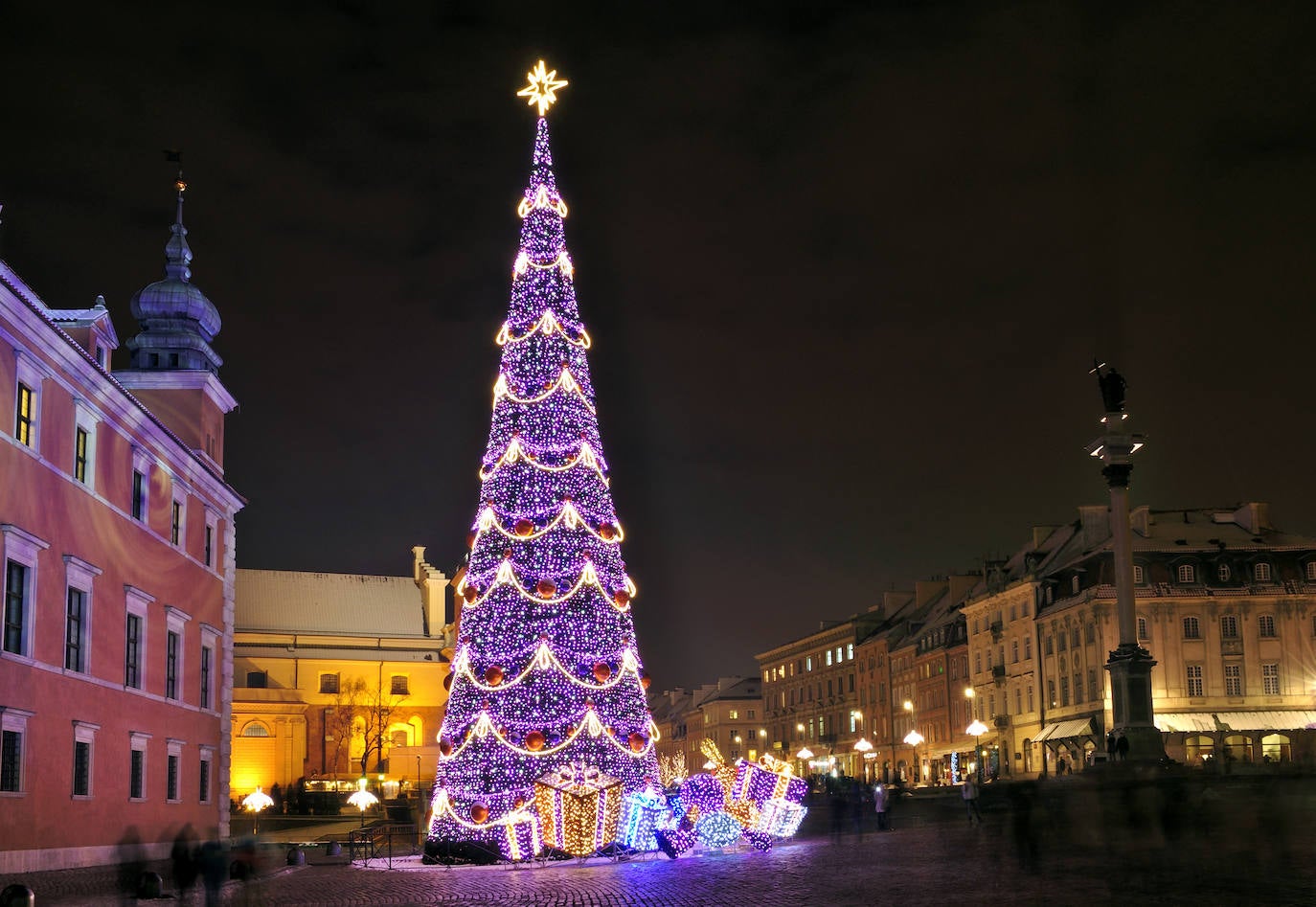 Con un deslumbrante despliegue de luces, bulliciosos puestos y diversas actividades, la capital polaca se transforma en un escenario festivo para dar la bienvenida a un monumental árbol en el corazón de la Plaza del Castillo. Las ferias de la Ciudad Vieja se sumergen en una atmósfera encantadora, ofreciendo una amplia variedad gastronómica para disfrutar y entrar en calor, destacando el famoso chocolate caliente. Además, en las principales plazas, aguarda una generosa pista de hielo que invita a patinar en buena compañía. El árbol de Navidad en la plaza cercana al Castillo en Varsovia se erige como el punto focal festivo. Esta histórica plaza, frente al antiguo Castillo Real que solía ser la residencia oficial de los monarcas polacos, se convierte en el epicentro navideño de Varsovia, Polonia, brindando a los visitantes una experiencia mágica en medio de la rica historia de la ciudad.