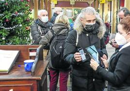 Un hombre enseña el pasaporte covid en la entrada a un bar en las navidades de 2021.