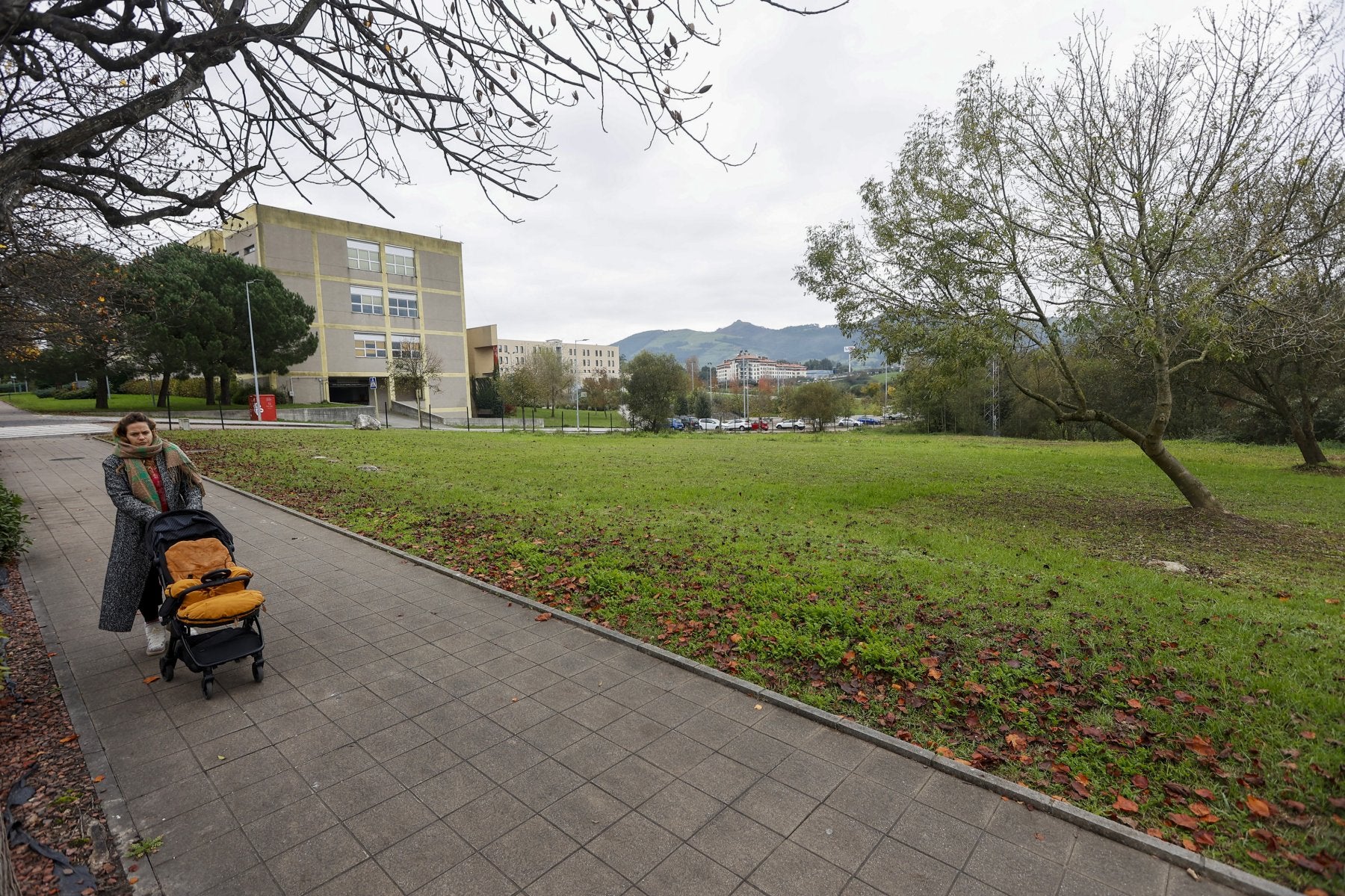 Una vecina camina junto a las fincas reservadas para la piscina olímpica, este otoño, en el entorno del campus de la UC.