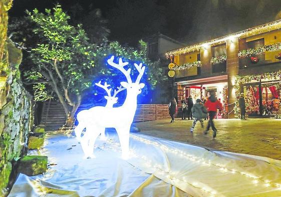 Vecinos de Quijano, en Piélagos, pasean frente a una de las casas decoradas por Navidad con luces y figuras.