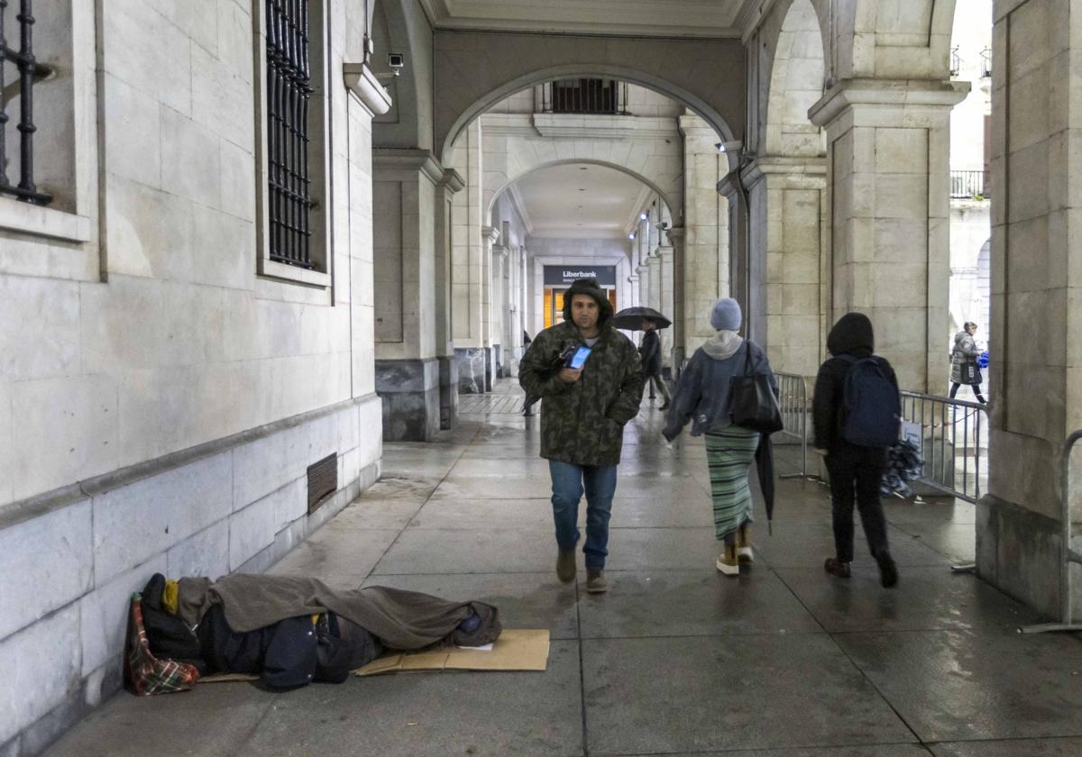 Una persona sintecho dormía sobre unos cartones y bajo una manta, en la noche del miércoles, en los soportales de la plaza Porticada de Santander.