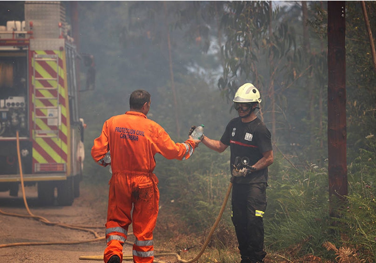 Un operario de Protección Civil y un bombero del 112 trabajan en un incendio.