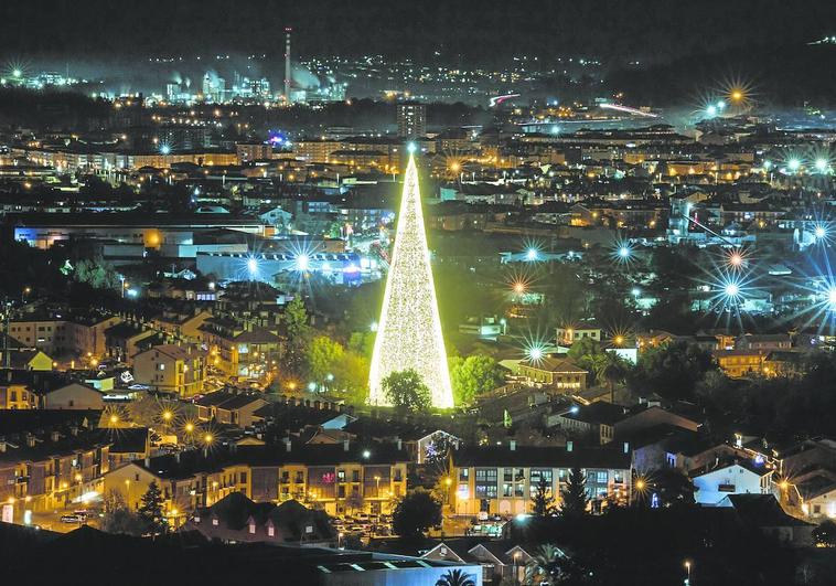 Vista nocturna de Cartes, en primer término y con el árbol de Navidad como punto más destacado. Al fondo, Torrelavega y la zona industrial, donde destaca la chimenea de Solvay.