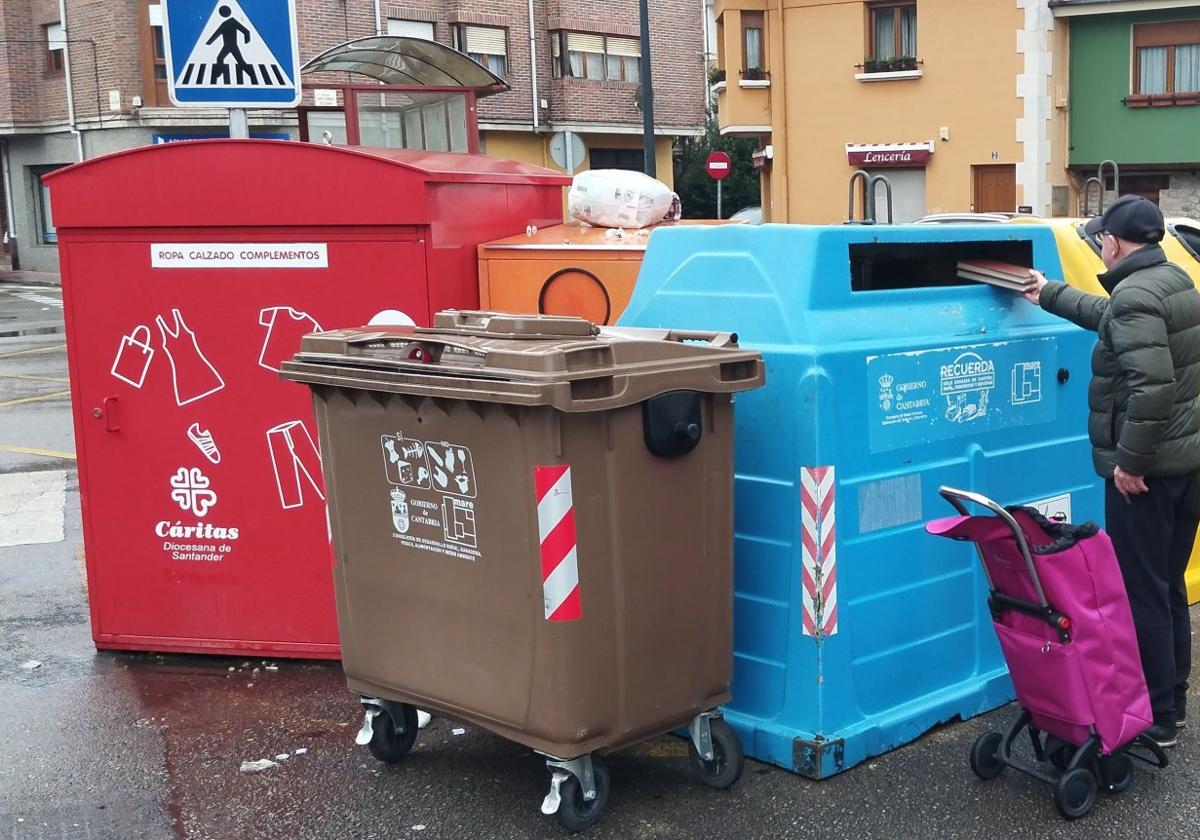 Un vecino de Los Corrales recicla en el contenedor de papel. Al lado, el de color marrón para biorresiduos, instalado en una experiencia piloto.