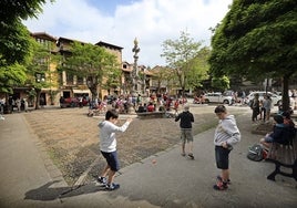 Varios niños juegan en la plaza de la fuente Tres Caños de Comillas.