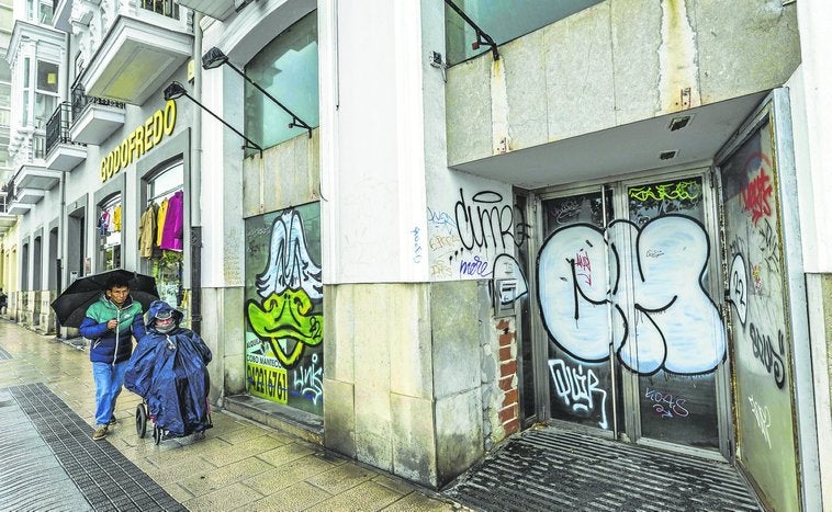 Uno de los locales vacíos del Paseo de Pereda, junto a la tienda Godofredo, lleno de grafitis.