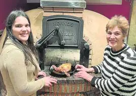 Patricia y su madre Mª Luisa, junto al gran horno que preside el comedor y que define la propuesta del restaurante.