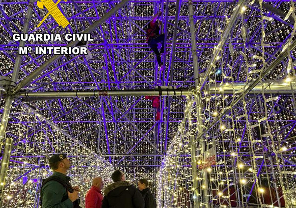 Un agente de la Guardia Civil observa, desde el pasillo que atraviesa por su parte baja el famoso árbol de Navidad de Cartes, cómo un operario trepa por el sistema de tubos que sustenta la estructura para llegar a la zona en la que quedó el dron, a 57 metros.