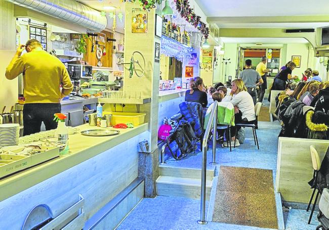 Todas las mesas del local están ocupadas en una tarde navideña con gente en la calle haciendo cola.