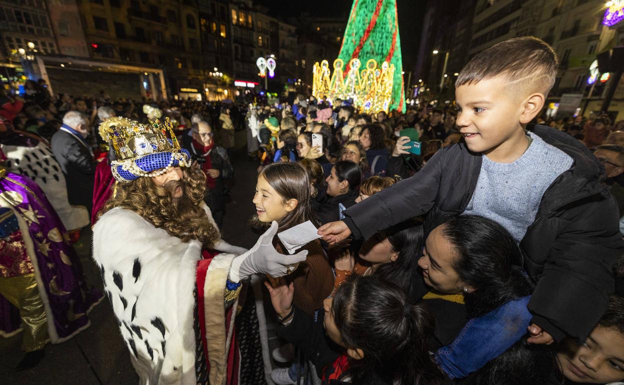 Un niño entrega su carta a Gaspar durante la cabalgata de Santander.