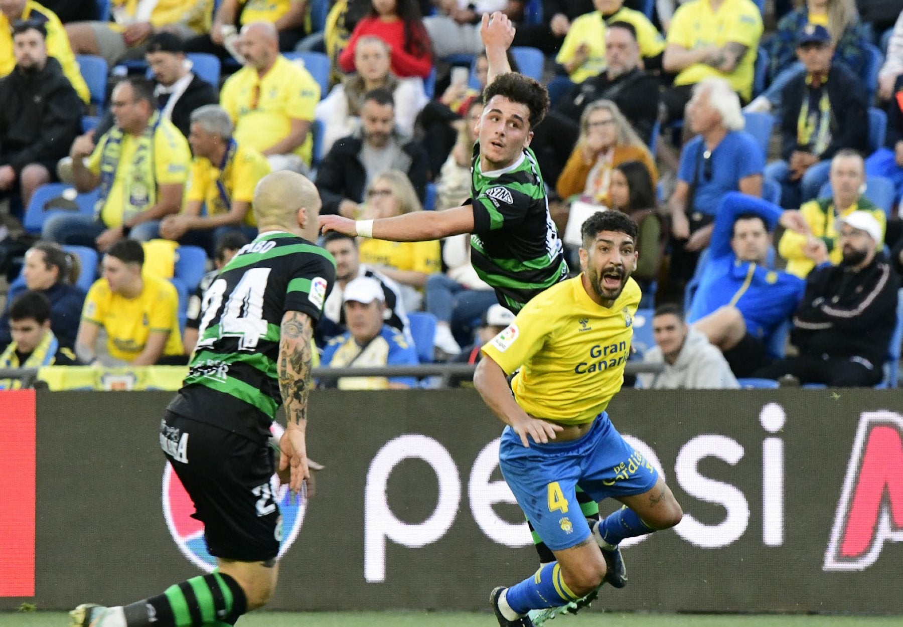 Yeray, en el centro, salta para llegar al balón ante la mirada de Pombo, de espaldas, y de Álex Suárez, de Las Palmas, ayer en el estadio de Gran Canaria. 