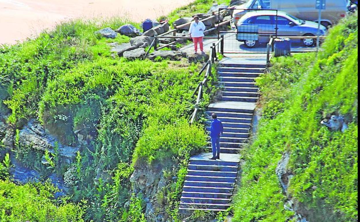 Varias personas buscan la manera de descender al pequeño arenal. 