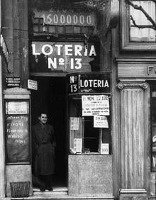 Imagen secundaria 2 - La administración número 13 de Loterías sigue hoy prácticamente igual que cuando se inauguró. Los rótulos, los cristales y los marcos son los originales, aunque el cartel más grande está actualmente cubierto con el oficial de Loterías del Estado. En la foto de arriba, Olga Gutiérrez, quien gestiona ahora el negocio con su socia Teresa Gajano.