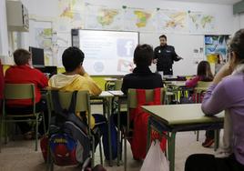 Un agente de policía imparte una charla en un aula sobre la prevención del acoso escolar.