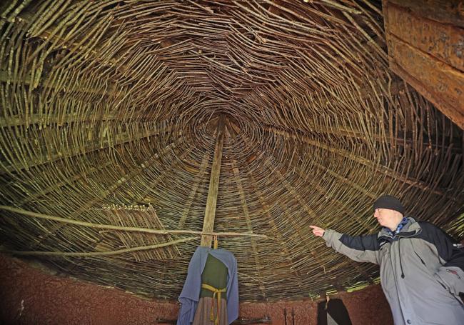 Un hombre señala el techo de escoba y las filtraciones de una de las cabañas.