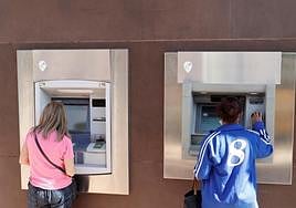 Imagen de archivo dedos clientas sacando dinero de una entidad bancaria.