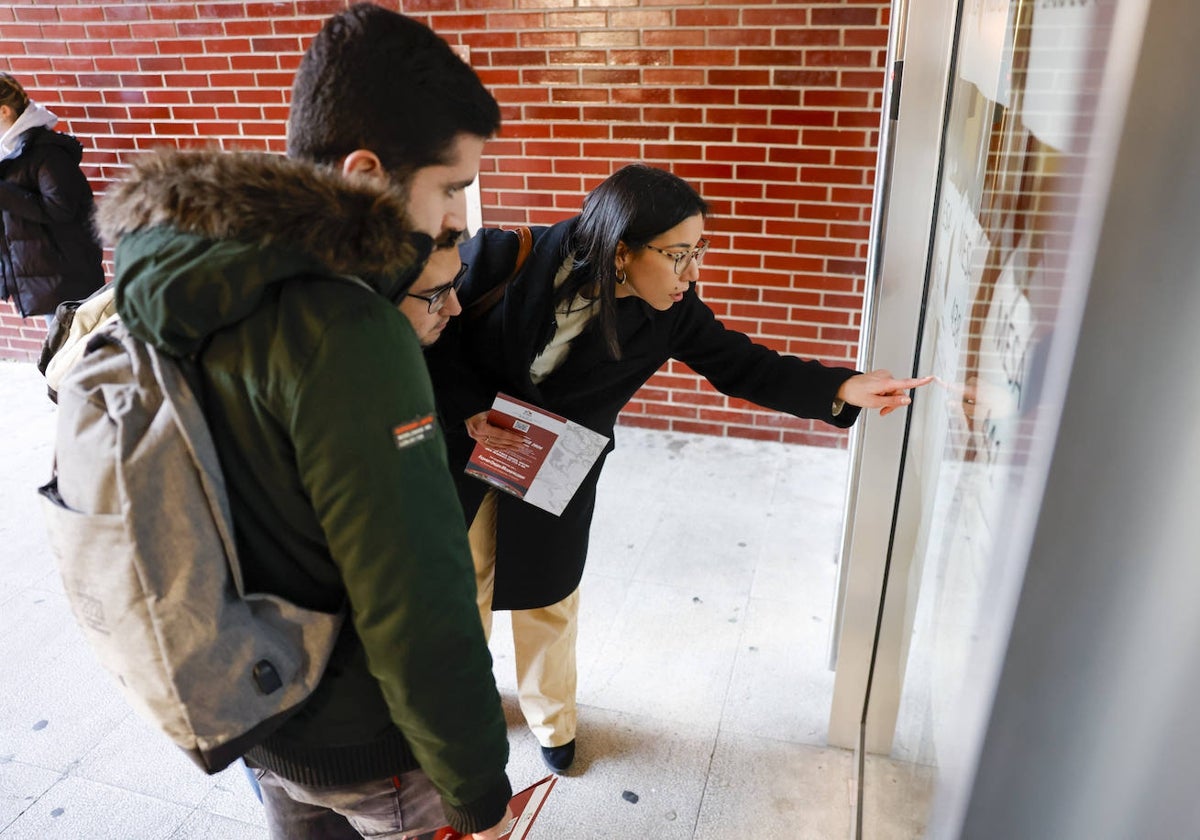 Tres aspirantes consultan las listas MIR colgadas en el acceso de la Facultad de Ciencias Económicas y Empresariales de la UC.