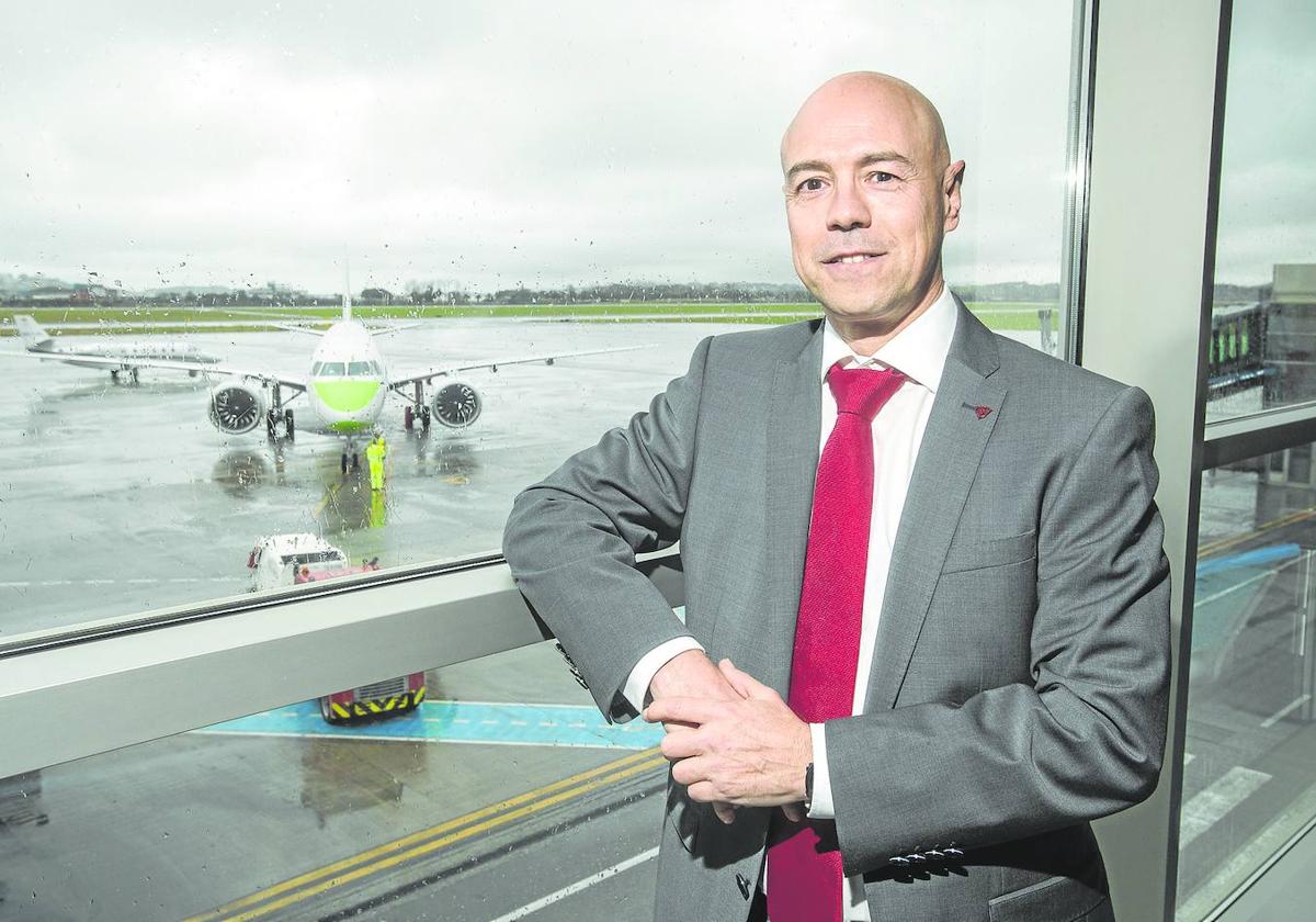 Miguel Ángel Salgado posa en una sala del aeropuerto con un avión sobre la pista como fondo.