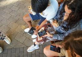 Tres jóvenes utilizan su teléfono móvil