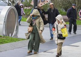 Dos mujeres se protegen del viento y la lluvia en Santander, este lunes.