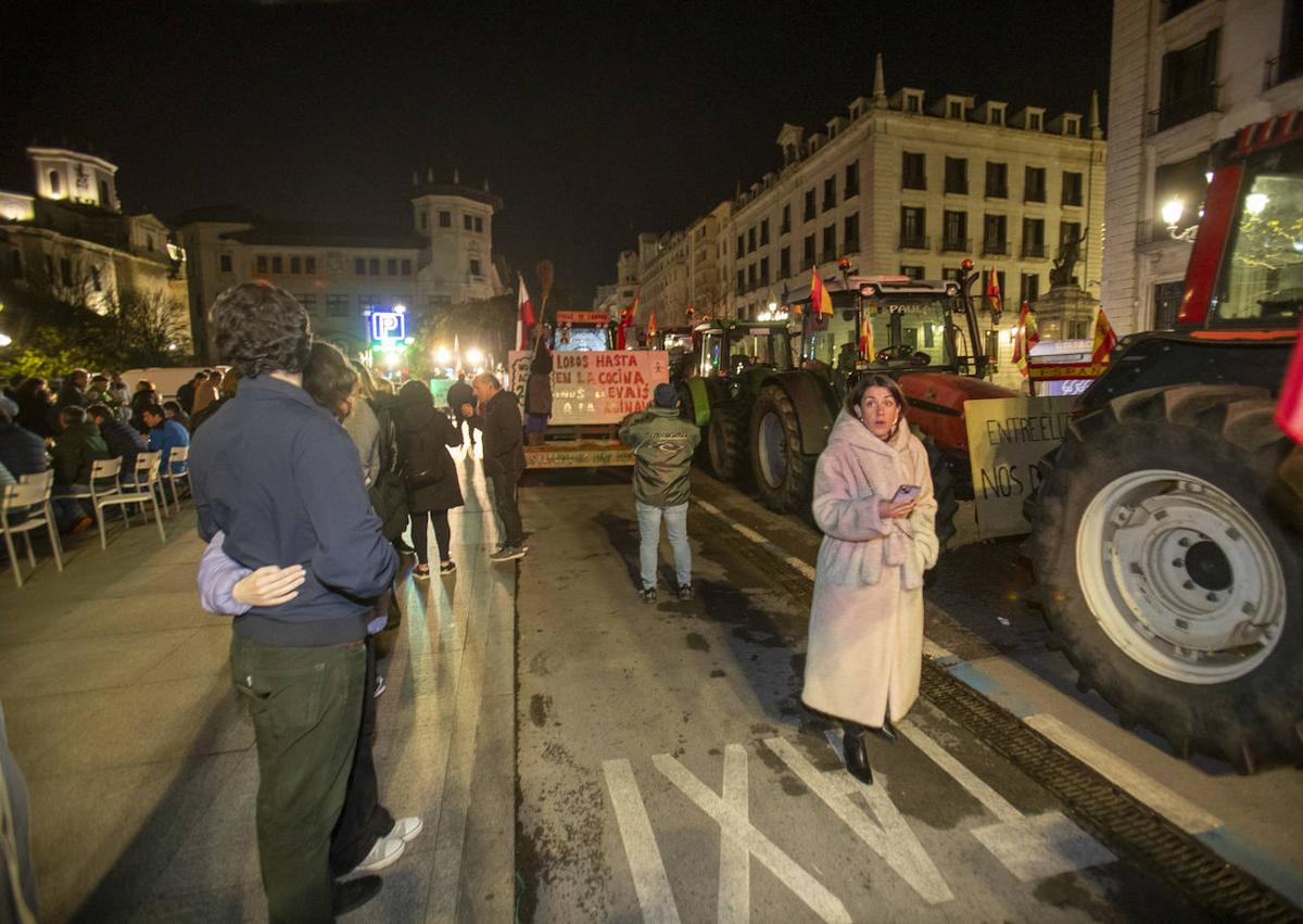 Imagen secundaria 1 - Los responsables de la protesta reparten bocadillos a los ganaderos que hicieron noche en Santander. A la izquierda, los tractores pernoctaron en un carril de la calle Calvo Sotelo. Y, a la derecha, la exdiputada Marta García corta jamón junto a una compañera para acompañar la cena