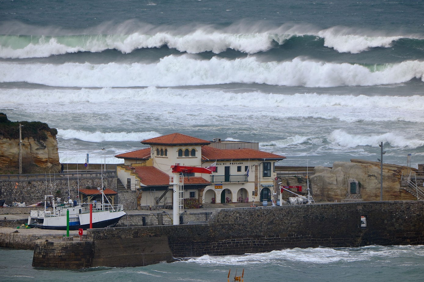 Las olas golpean el puerto de Comillas. 