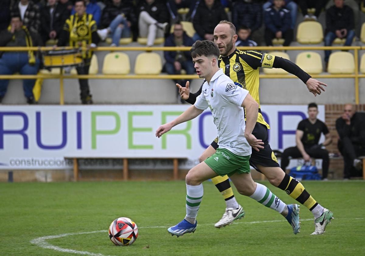 Neco, del Rayo, lleva el balón ante Marcos, del Cayón.