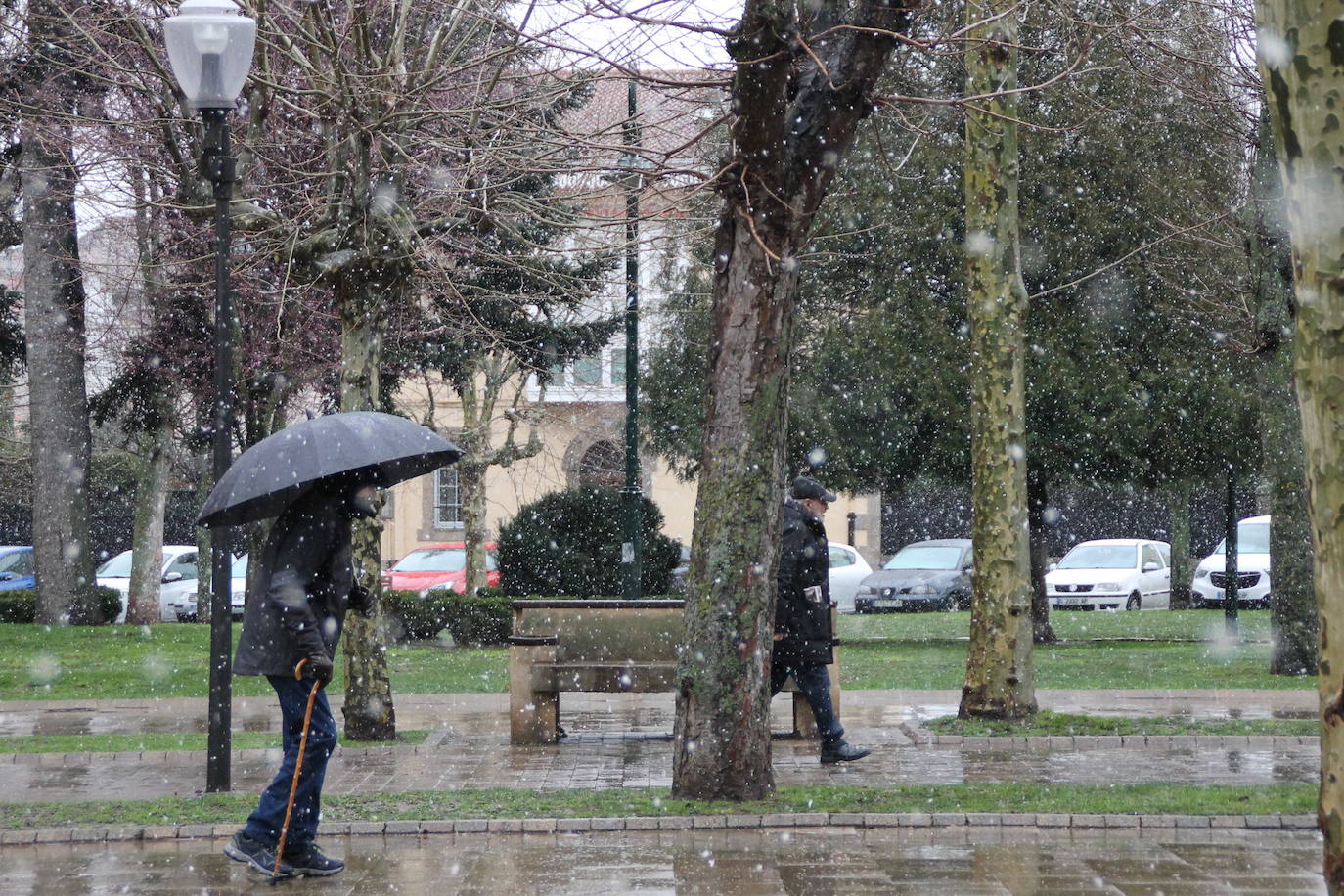 Dos hombres pasean abrigados bajo los copos de nieve en Reinosa.