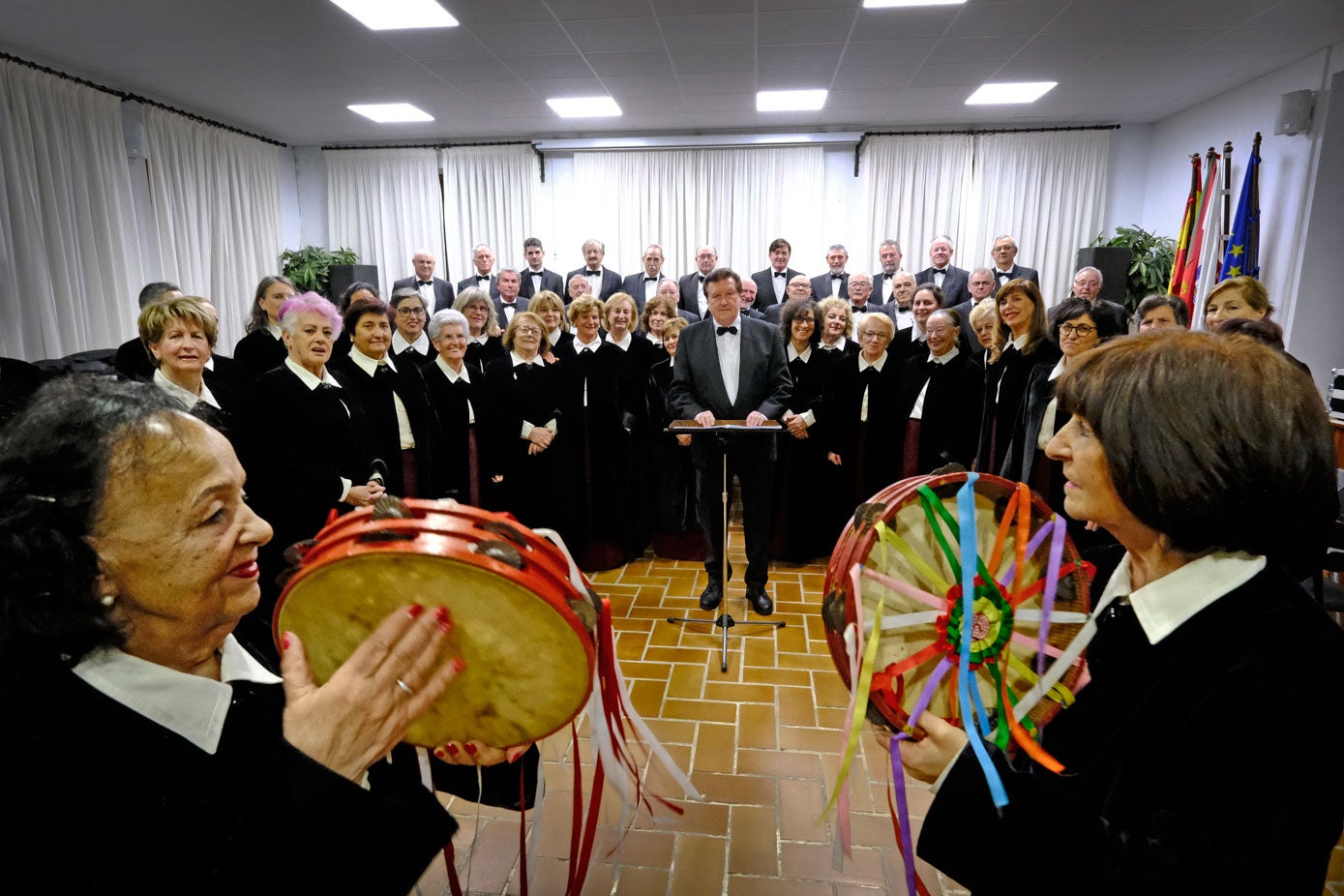 Dos pandereteras acompañan a los coralistas en el ensayo general.