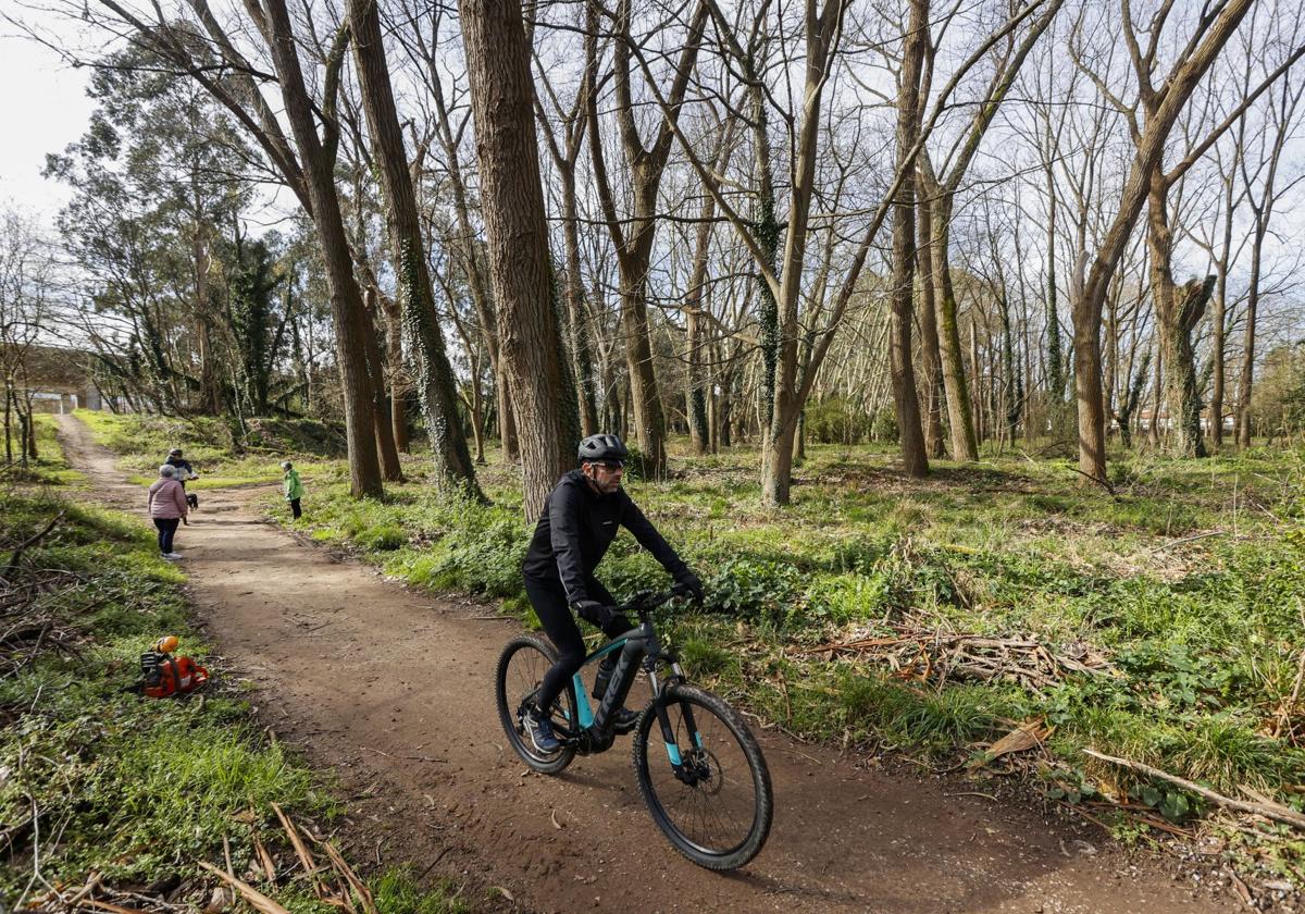 Un ciclista circula en una de las sendas del parque de Las Tablas tras dejar atrás a unas paseantes, ayer, en Torrelavega.