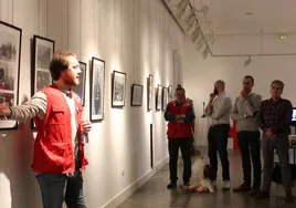Un miembro de la Cruz Roja explica parte de la exposición de imágenes a miembros del equipo de gobierno.