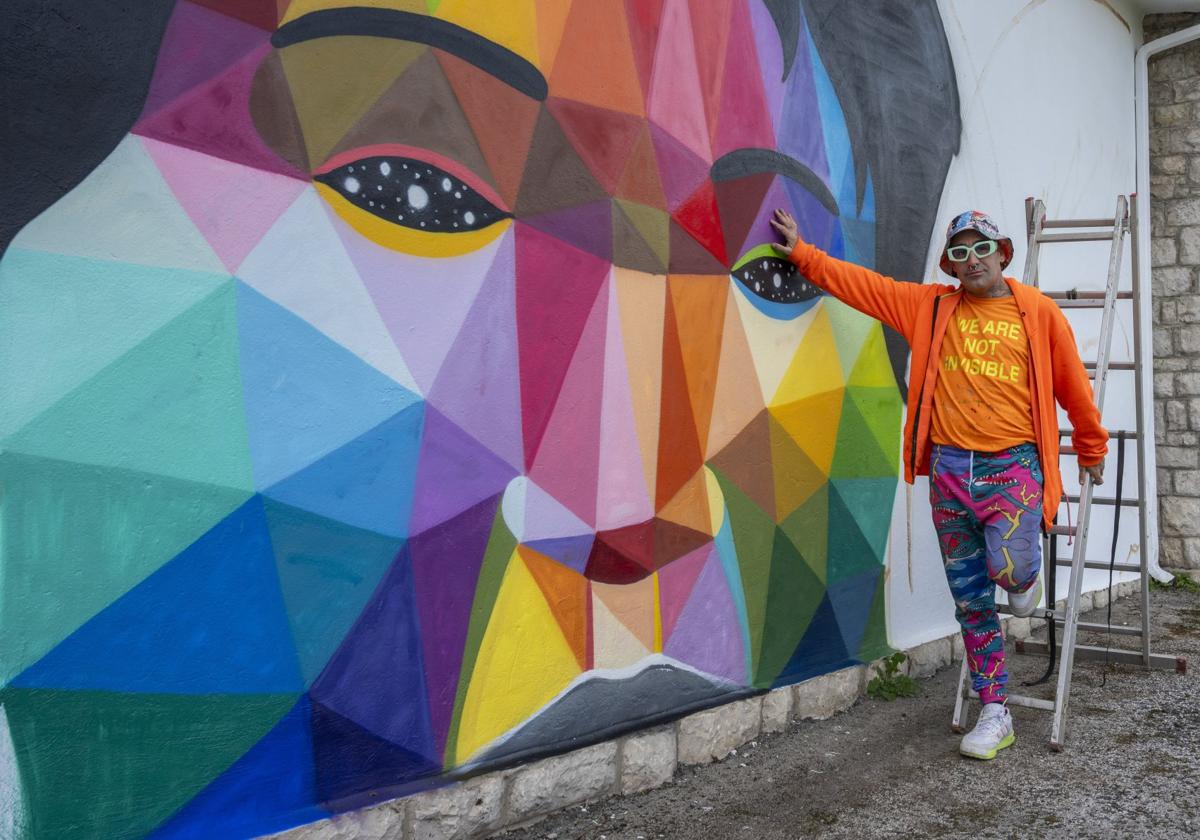 Okuda posa en una de las caras de mujer que ha realizado en el aula de La Penilla.