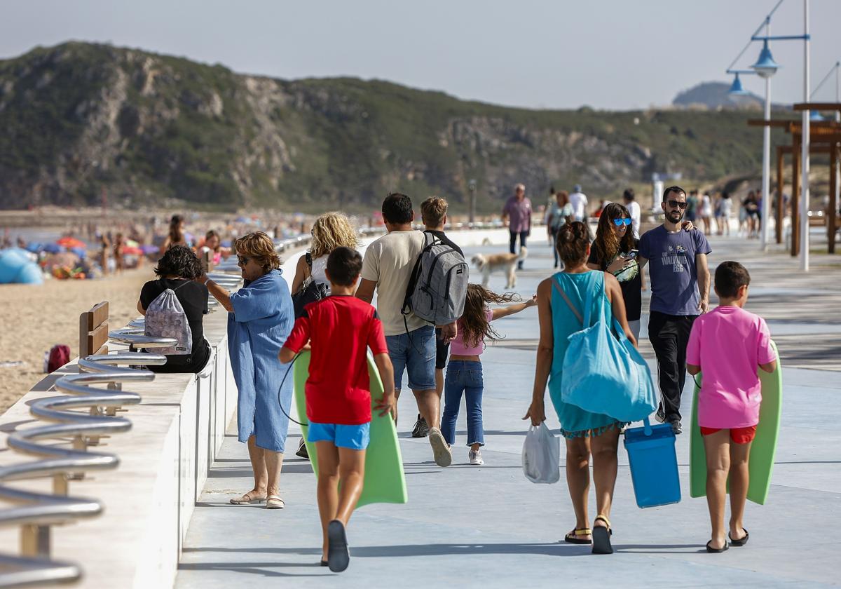 Varias personas caminan por el paseo marítimo de Suances, uno de los municipios cántabros que más turistas recibe cada verano.