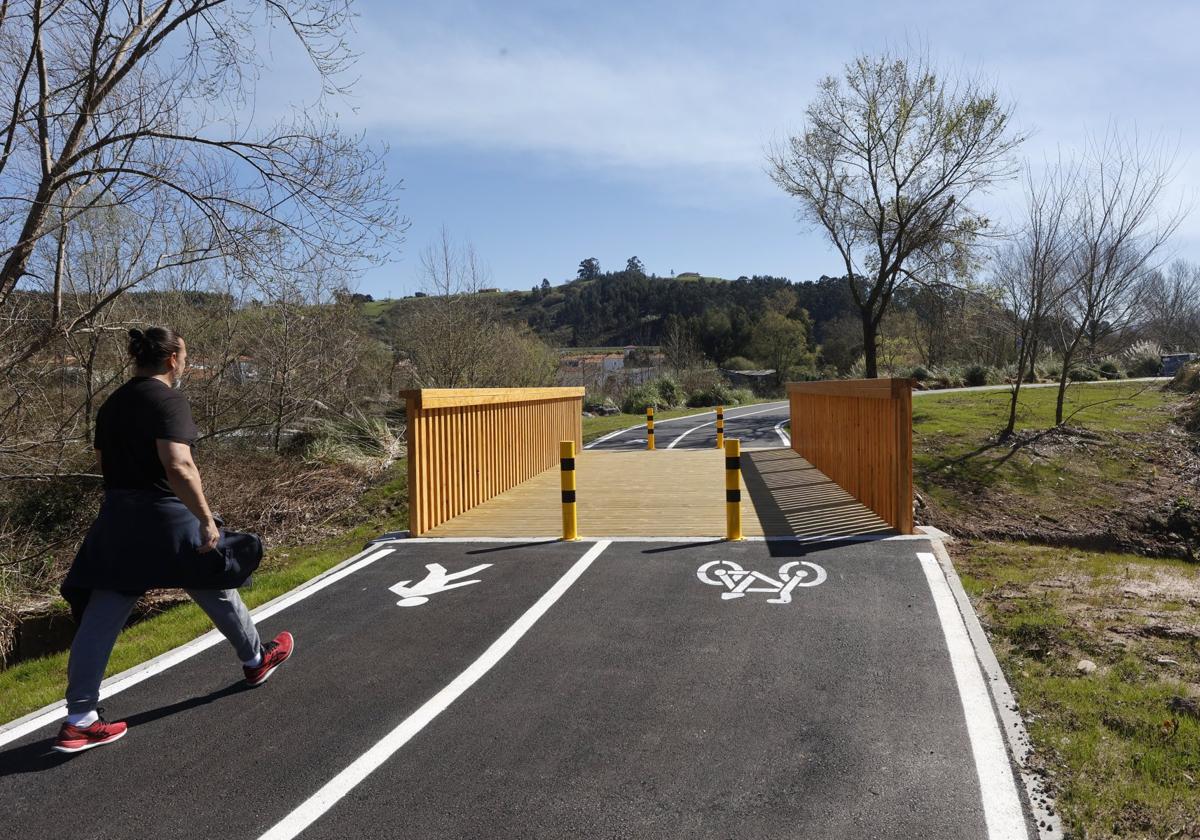 Un ciudadano pasea junto a la nueva pasarela de madera, instalada sobre el canal de Sniace.