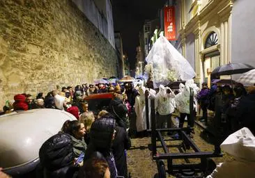 La Merced, protegida con plásticos, durante el traslado hasta la carpa de La Porticada, acompañada de los cofrades