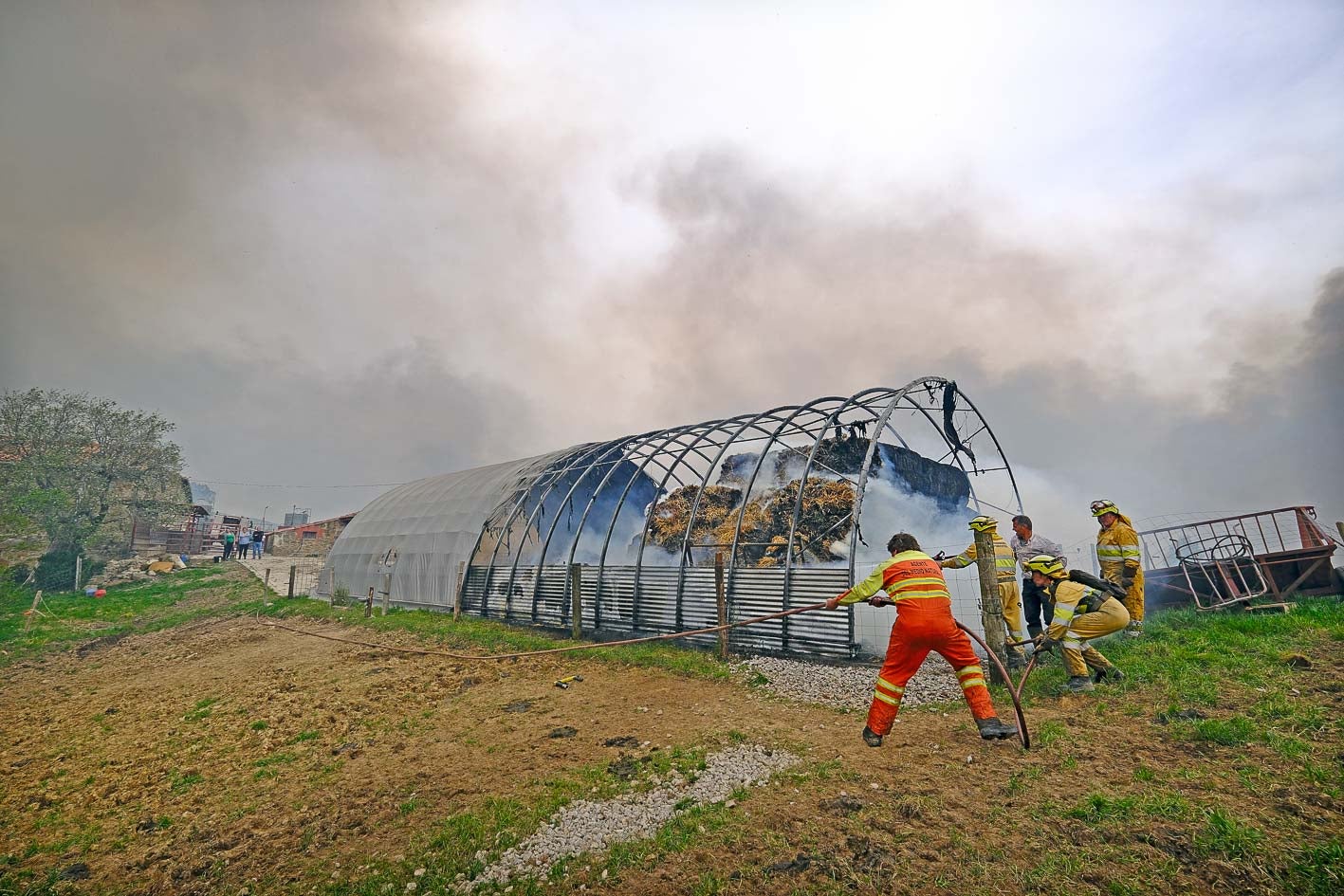 Los bomberos forestales y Elías Cobo, propietario de la ganadería de La Busta, tratan de sofocar las llamas. 