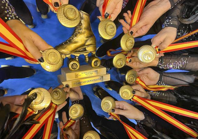 Los patinadores muestran sus medallas de oro y la bota dorada que han recibido como trofeo.