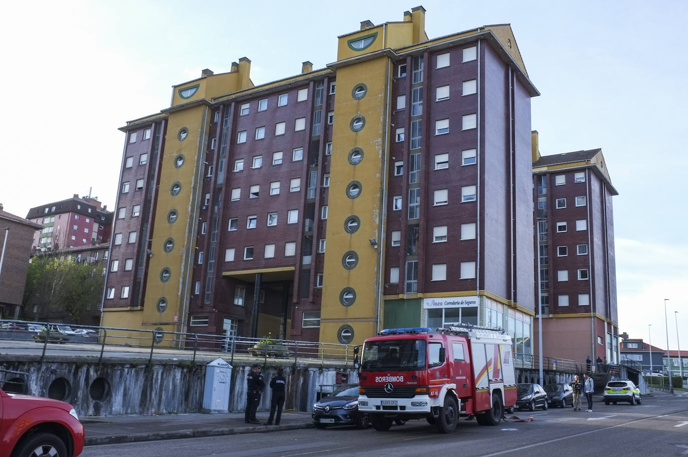 Policías y bomberos, ante uno de los edificios que comparten el garaje siniestrado.