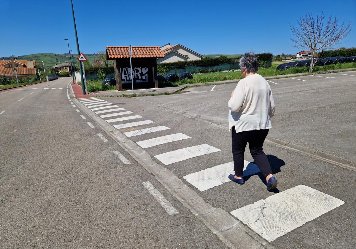 Una vecina de Hinojedo pasa junto a la marquesina del autobús.