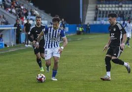 Chus Ruiz controla la pelota ante dos jugadores del Langreo.