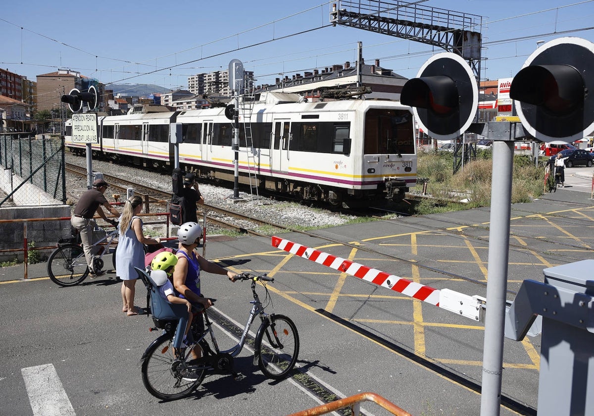 Vecinos esperan frente al paso a nivel de Pablo Garnica, mientras un tren abandona la ciudad, el año pasado, en Torrelavega.