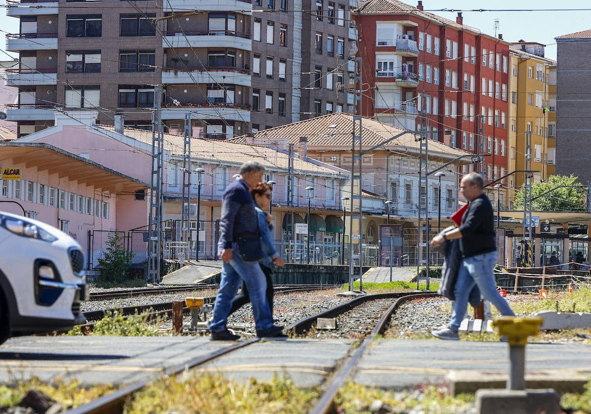 Vecinos cruzan el paso a nivel de Pablo Garnica, con la estación de Torrelavega-Centro al fondo.