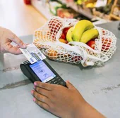 Un demandante de ayuda alimentaria paga su compra en un supermercado con la tarjeta monedero de Cáritas Diocesana.
