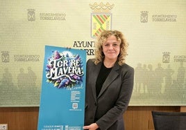 La edil de Festejos, Patricia Portilla, sostiene el cartel del evento, este lunes, en Torrelavega.