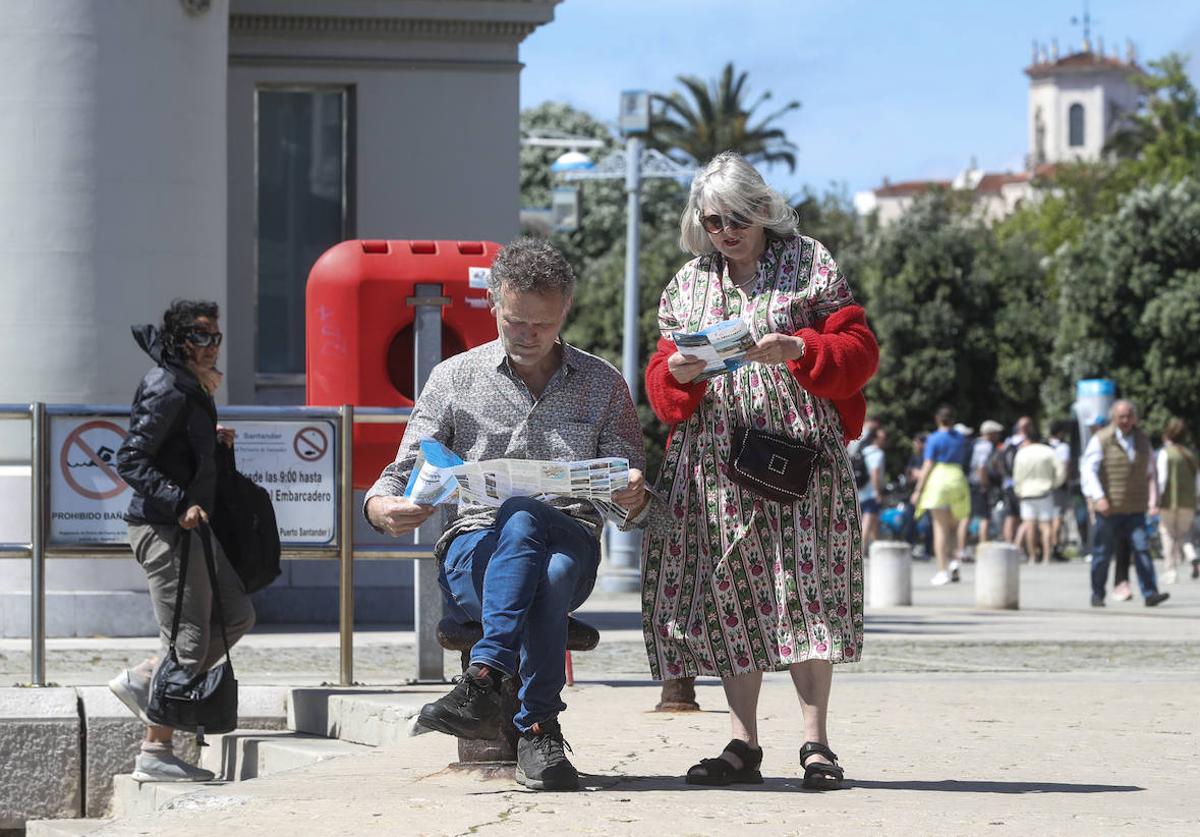 Dos turistas consultan un folleto informativo de Santander frente al Palacete del Embarcadero.